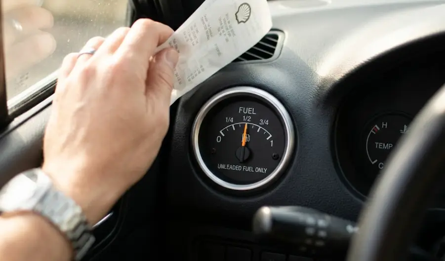 Car fuel gauge near half tank with gas receipt