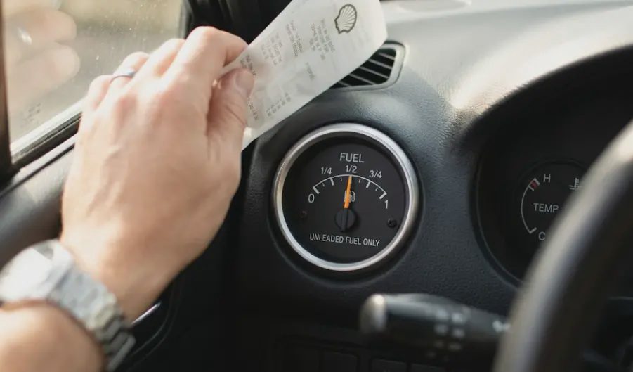 Car fuel gauge near half tank with gas receipt