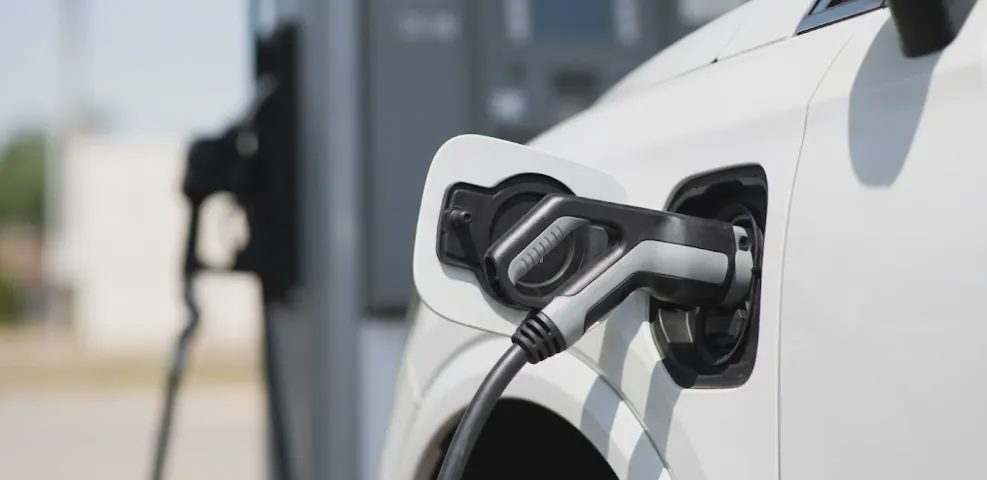  EV charging port plugged with gas pump blurred in background